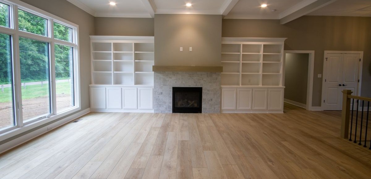 Light oak wide-plank flooring in a family room with whitewashed brick fireplace