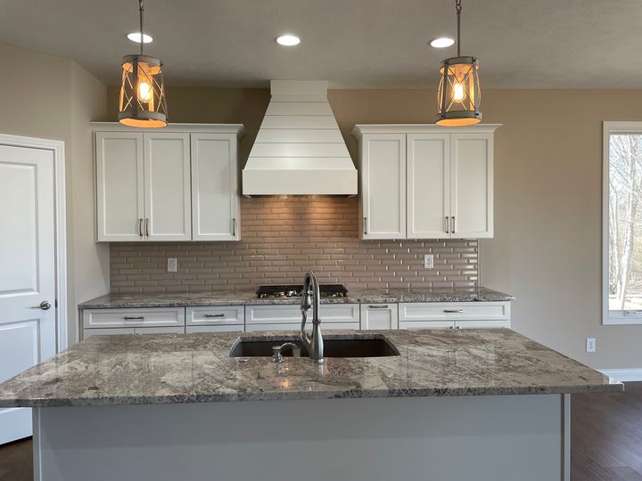 Taupe beveled subway tile backsplash in a white kitchen with granite counters and shiplap range hood in Danville, IN