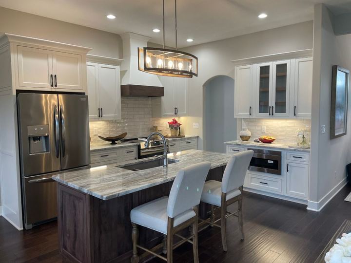 Kitchen with cream beveled subway tile backsplash, granite island and dark hardwood flooring in Plainfield, IN