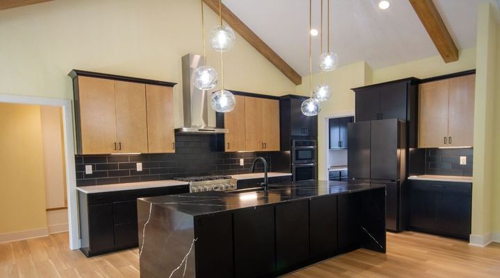 Kitchen with black subway tile backsplash, waterfall quartz island and wood-look plank flooring in Avon, IN