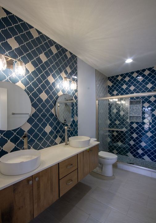 Hall bathroom with navy and white arabesque tile feature wall, floating wood vanity and vessel sinks in Avon, IN