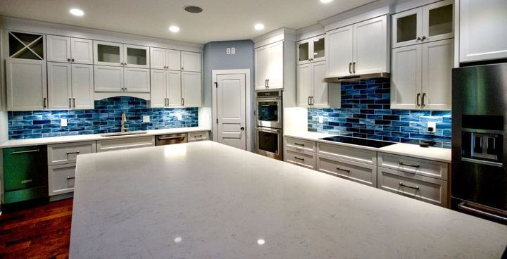 White kitchen with iridescent blue glass subway tile backsplash, quartz island and dark hardwood floor in Avon, IN