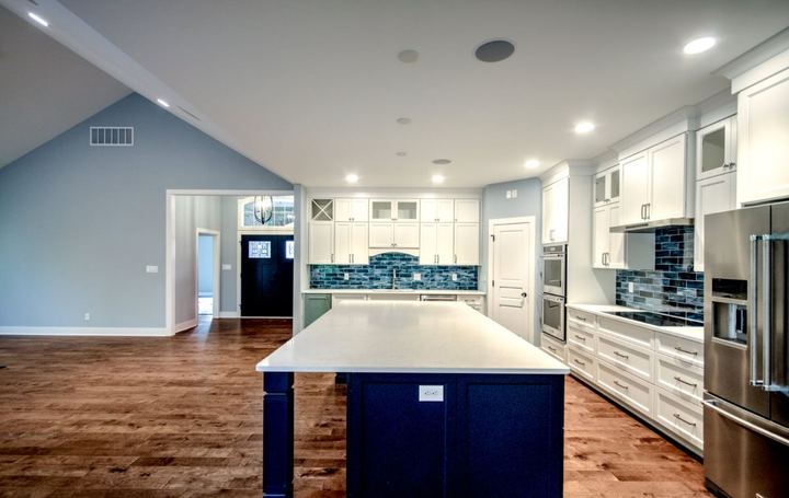 White kitchen with deep blue glass subway backsplash, navy island and hand-scraped hardwood floors in Avon, IN