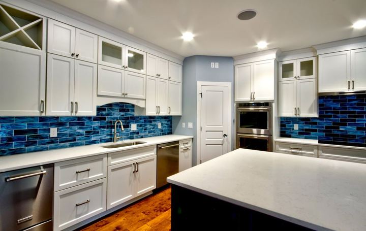 Kitchen wall run with vivid blue glass subway tile backsplash, white cabinets and hardwood floor in Avon, IN