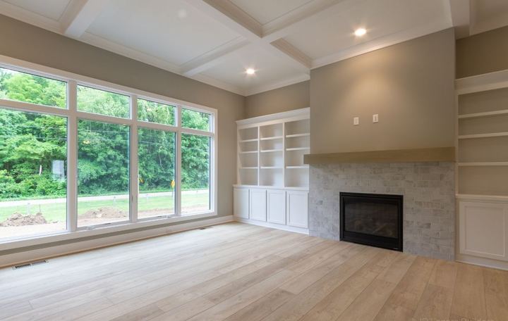 Living room with gray brick-look tile fireplace, built-ins and light oak plank flooring in Avon, IN