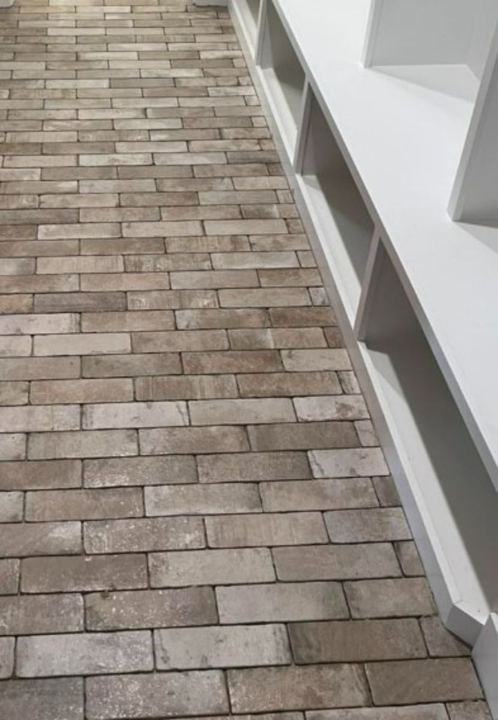 Mudroom with rustic brick paver tile floor laid diagonally beside white built-in bench cubbies in Pittsboro, IN