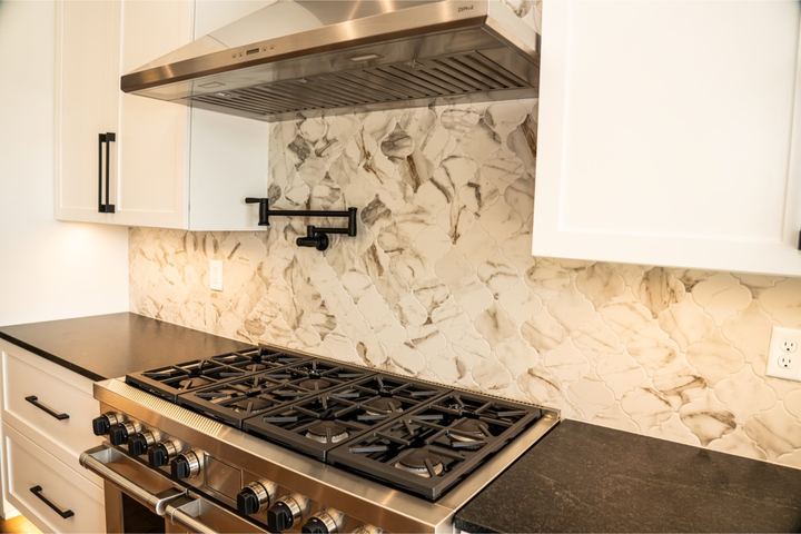 Calacatta marble arabesque mosaic backsplash behind a pro-style range with black countertops and pot filler in Brownsburg, IN
