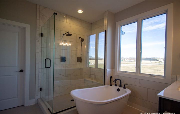 Master bath with calacatta-look tile corner shower, freestanding tub, tile wainscot and black fixtures in Avon, IN