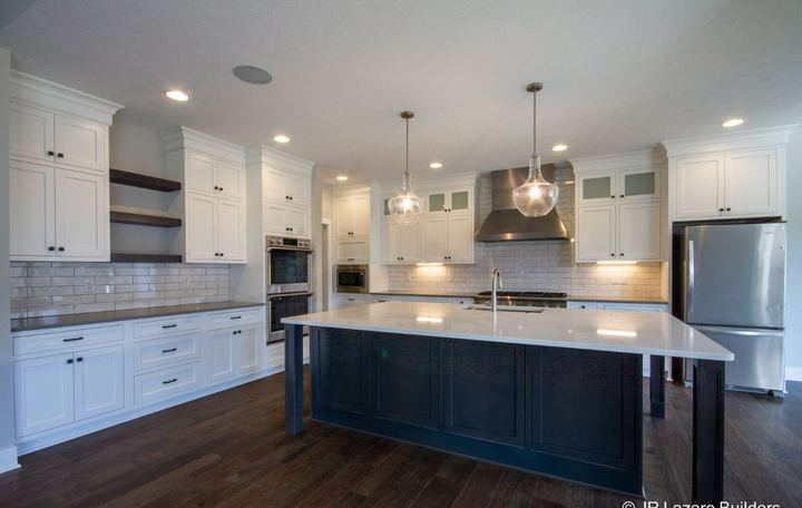 White kitchen with Carrara-look subway backsplash, navy island and dark hickory hardwood floors in Avon, IN