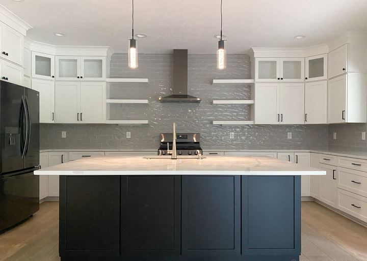 Glossy gray subway backsplash run to the ceiling in a white kitchen with black island and quartz top in Avon, IN