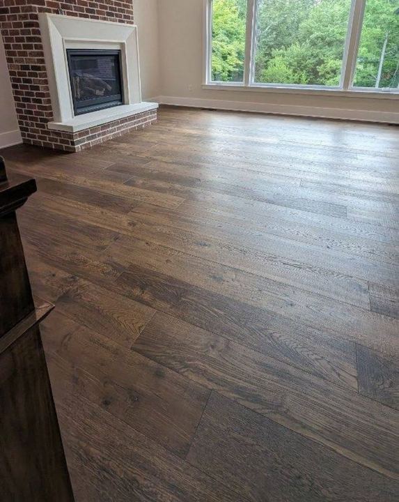 Dark character-grade oak hardwood flooring in a living room with brick fireplace in Avon, IN
