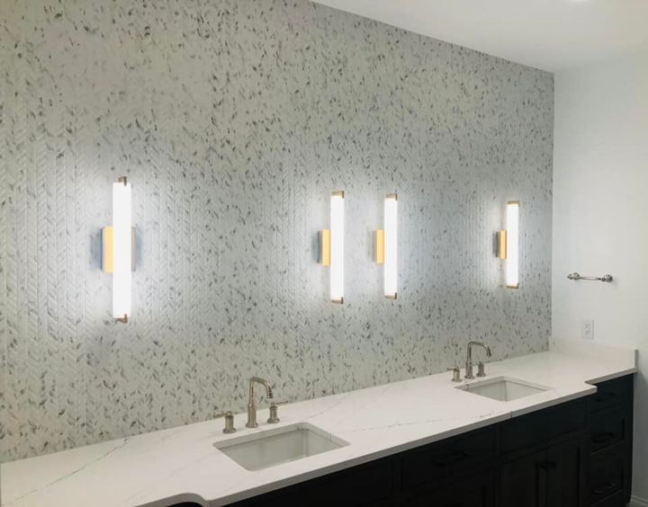 Double vanity bathroom with white chevron mosaic accent wall, quartz countertop and vertical sconce lighting in Danville, IN