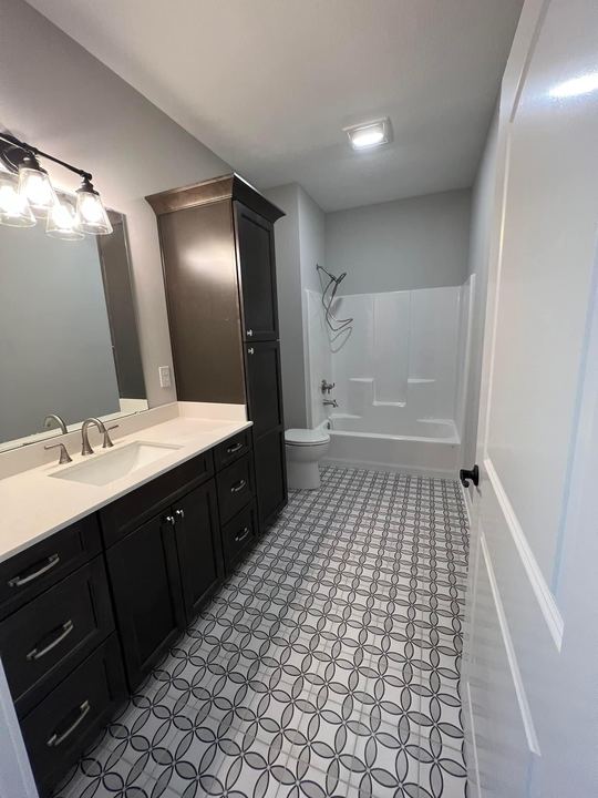 Full bathroom with gray interlocking-circle pattern tile floor, espresso vanity and linen tower in Brownsburg, IN