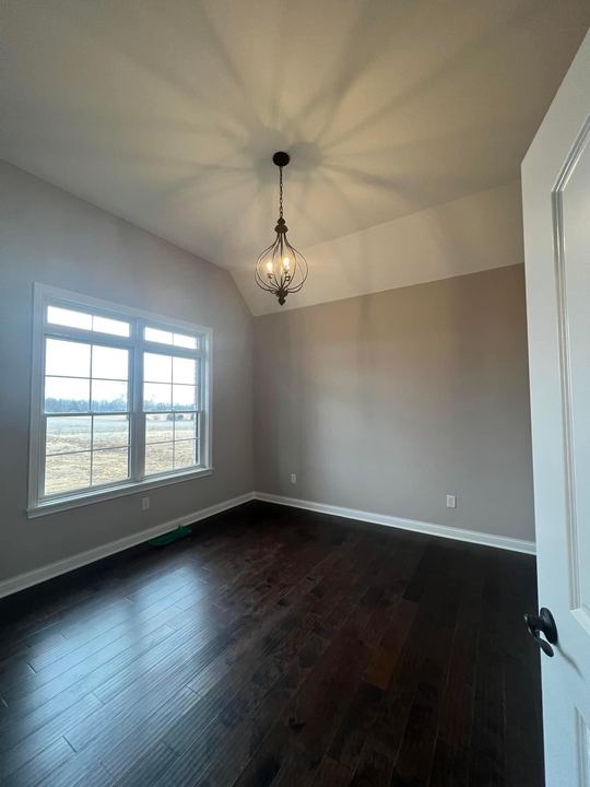 Espresso-stained hardwood flooring in a vaulted bedroom with chandelier and large windows in Brownsburg, IN
