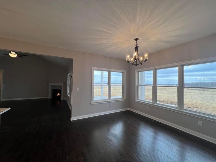 Espresso hardwood plank flooring in a dining room with chandelier, corner fireplace and prairie views in Brownsburg, IN