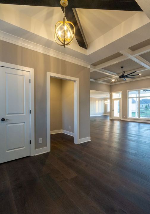 Open floor plan with dark hand-scraped hardwood flooring, coffered ceilings and gold orb chandelier in Avon, IN