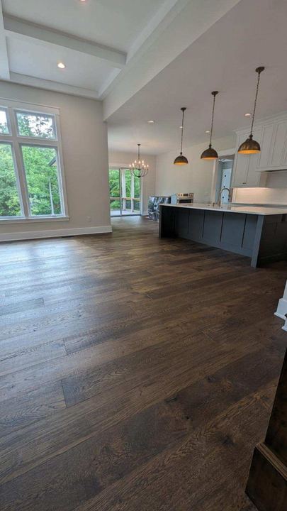 Open kitchen and living area with dark-stained wide plank oak hardwood flooring and slate blue island in Avon, IN