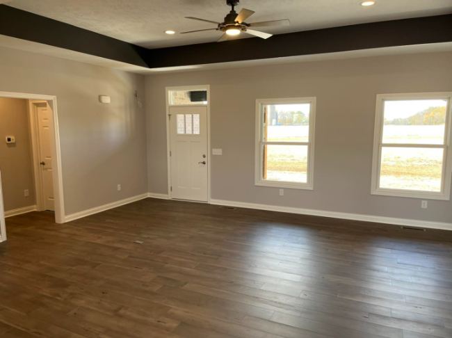 Dark brown luxury vinyl plank flooring in a bright living room with tray ceiling in Danville, IN