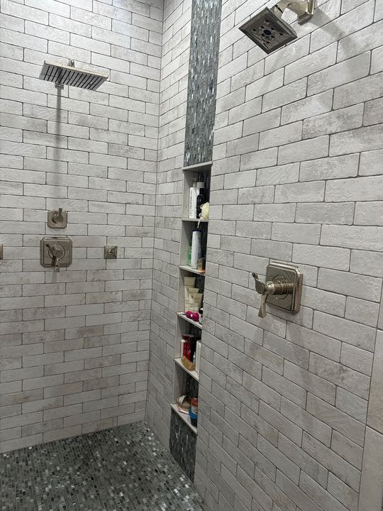 Walk-in shower with white brick-look subway tile, glass mosaic accent stripe, tall shelf niche and dual shower heads in Avon, IN