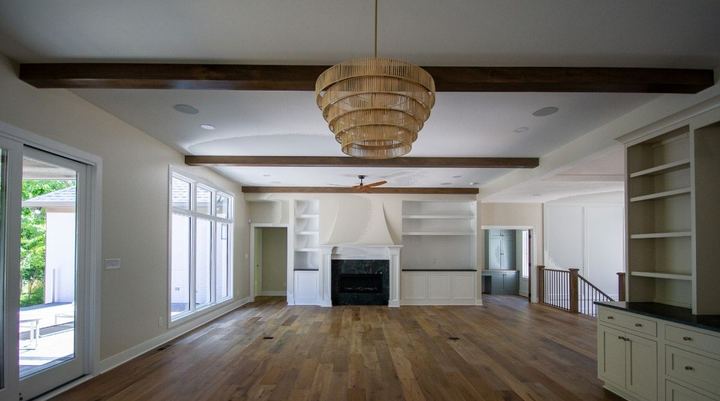 Wide-plank engineered hardwood in a great room with wood beams, built-ins and marble fireplace in Avon, IN
