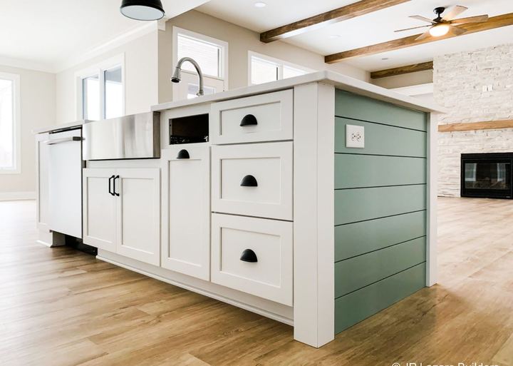 Kitchen island with farmhouse sink and shiplap end panel over warm-toned luxury vinyl plank flooring in Avon, IN