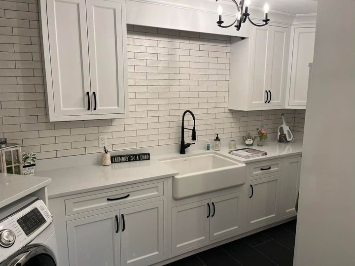 Laundry room with white subway tile wall, farmhouse sink, black faucet and charcoal plank tile floor in Pittsboro, IN