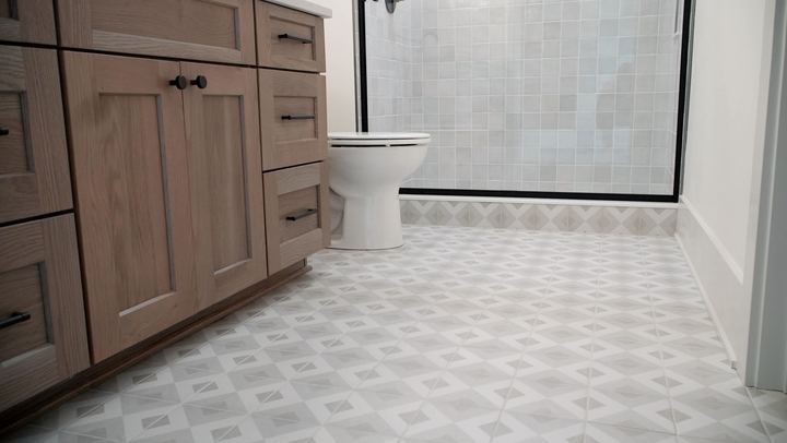Bathroom with gray and white geometric patterned tile floor, oak vanity and square tile shower wall in Plainfield, IN