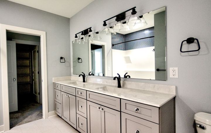 Jack-and-Jill bathroom with light tile floor, gray double vanity, marble top and navy mosaic shower accent in Avon, IN