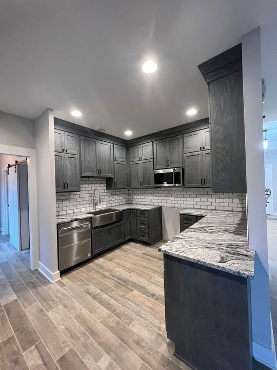 Gray shaker kitchen with white subway backsplash, granite counters and wood-look plank tile floor in Brownsburg, IN