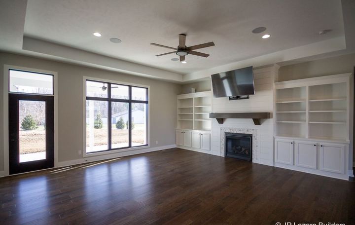 Living room with dark hand-scraped hardwood plank flooring, shiplap fireplace with mosaic surround and built-ins in Avon, IN