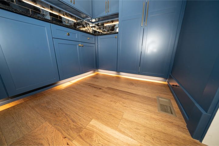 Light hickory hardwood flooring in a blue butler's pantry with under-cabinet lighting in Plainfield, IN