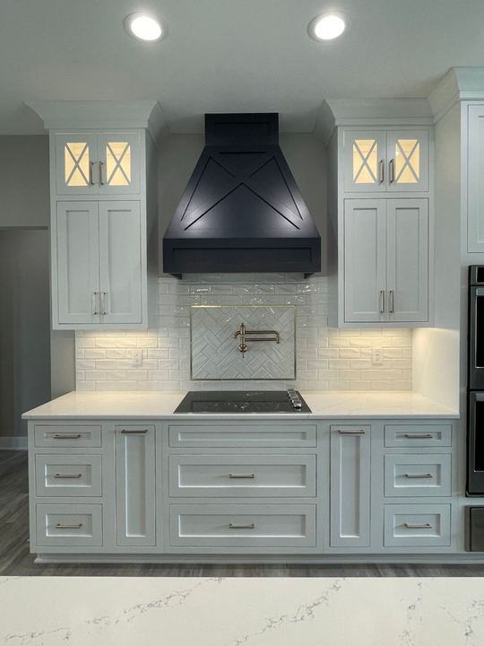 White kitchen with beveled subway backsplash, gold-framed herringbone accent panel and navy range hood in Plainfield, IN