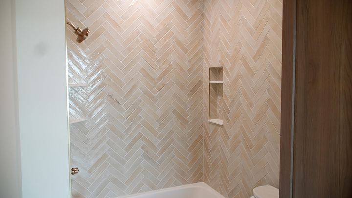 Tub surround with cream herringbone tile, recessed niche and brushed gold fixtures in Avon, IN