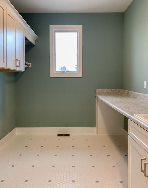 Laundry room with white hexagon mosaic tile floor accented by gray dots and sage green walls in Avon, IN