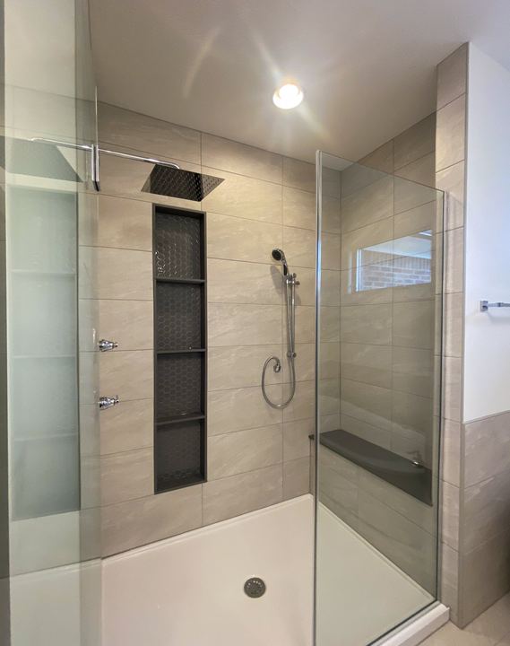Glass walk-in shower with taupe large-format tile, stacked hex mosaic niches, rain head and hand shower in Avon, IN