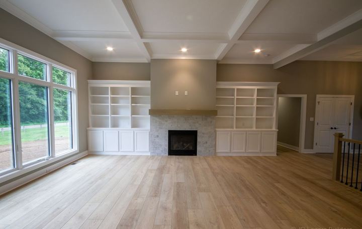Family room with light oak wide plank flooring, whitewashed brick fireplace and built-in shelving in Avon, IN