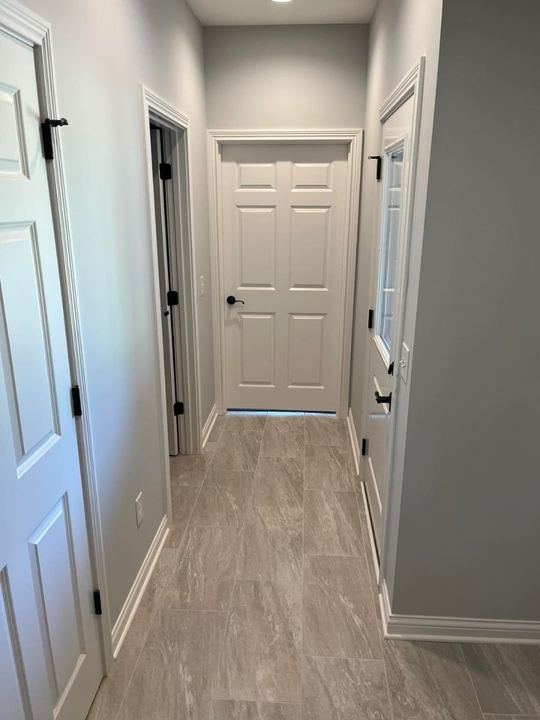 Back hallway with greige luxury vinyl tile flooring, gray walls and white six-panel doors in Avon, IN