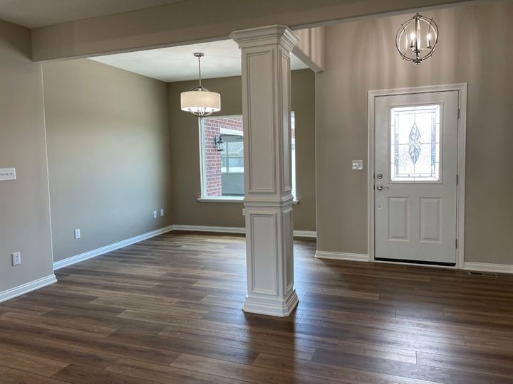 Warm brown luxury vinyl plank flooring in an entryway and dining room with white column detail in Plainfield, IN