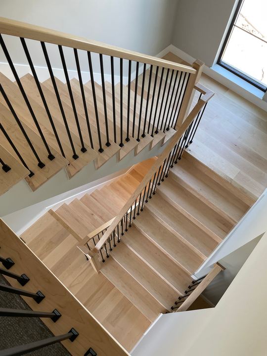 Custom maple staircase with black metal balusters and matching hardwood floors in Plainfield, IN