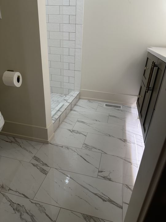 Polished marble-look porcelain tile bathroom floor with white subway shower entry and dark vanity in Avon, IN