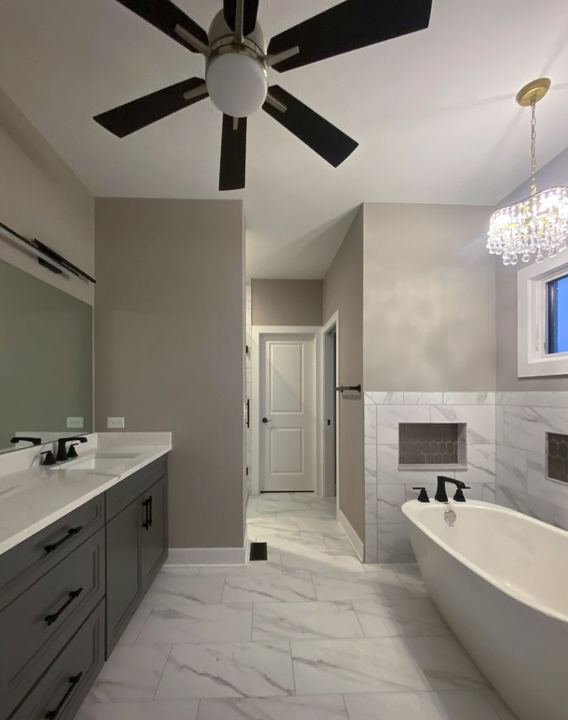 Master bath with marble-look tile floor and wainscot, hex-tile niches, freestanding tub and gray vanity in Avon, IN