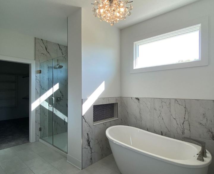 Master bath with marble-look tile wainscot, freestanding tub, penny tile niche and glass shower in Avon, IN