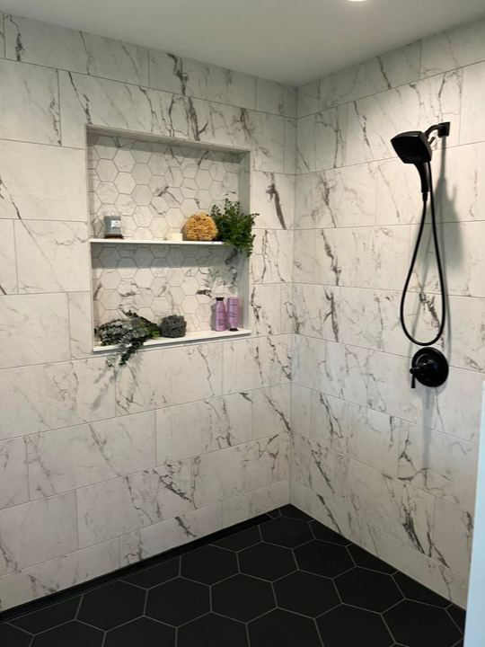 Custom marble-look tile shower with black hexagon floor, shelved niche and matte black fixtures in Pittsboro, IN