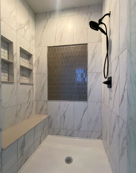 Walk-in shower with marble-look walls, bronze hexagon mosaic feature panel, bench seat and dual niches in Avon, IN