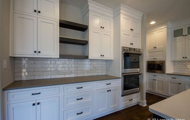 White kitchen with polished marble subway tile backsplash, floating shelves and dark hardwood floor in Avon, IN