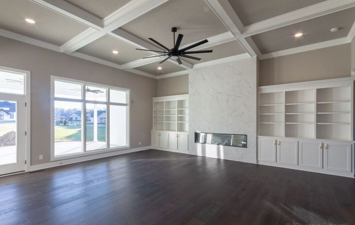 Living room with floor-to-ceiling marble-look tile fireplace surround, built-ins and dark hardwood floors in Avon, IN