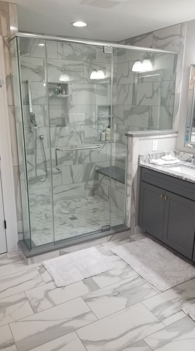 Glass walk-in shower with marble-look tile walls, hex mosaic pan, bench and matching marble porcelain bathroom floor in Avon, IN