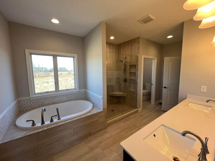 Master bathroom with mosaic-trimmed drop-in tub, tiled walk-in shower and wood-look tile floor in Brownsburg, IN