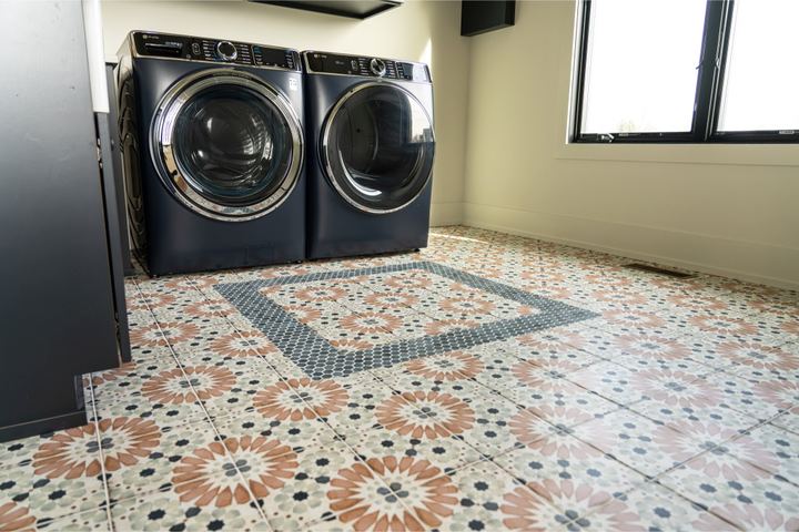 Laundry room with colorful Moroccan-pattern tile floor and inset border rug design under navy washer and dryer in Brownsburg, IN