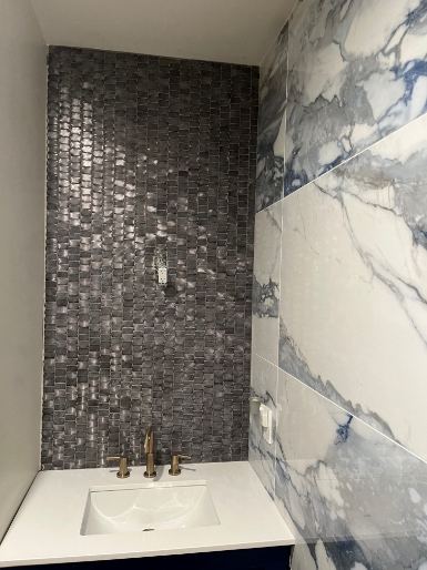 Powder room vanity with gray glass mosaic accent wall, blue-veined marble tile and gold faucet in Indianapolis, IN